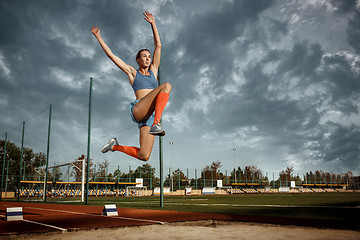 Image showing Female athlete performing a long jump during a competition