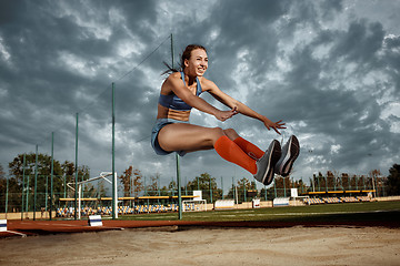 Image showing Female athlete performing a long jump during a competition