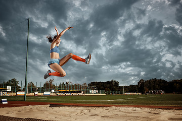 Image showing Female athlete performing a long jump during a competition