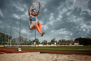 Image showing Female athlete performing a long jump during a competition