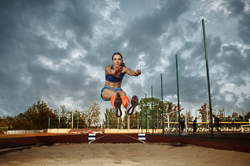 Image showing Female athlete performing a long jump during a competition