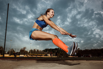 Image showing Female athlete performing a long jump during a competition