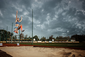 Image showing Female athlete performing a long jump during a competition