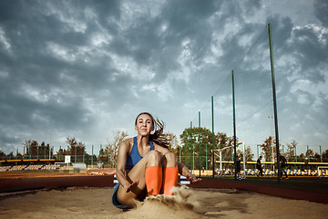 Image showing Female athlete performing a long jump during a competition