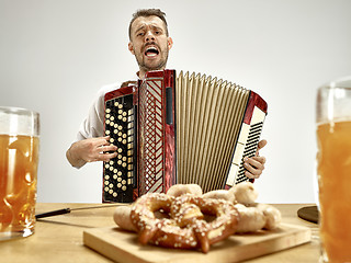 Image showing Man in traditional bavarian clothes playing accordion. Oktoberfest