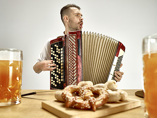 Image showing Man in traditional bavarian clothes playing accordion. Oktoberfest