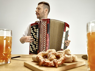 Image showing Man in traditional bavarian clothes playing accordion. Oktoberfest