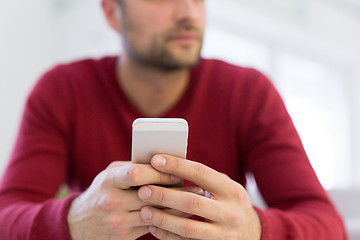 Image showing young man using a mobile phone  at home