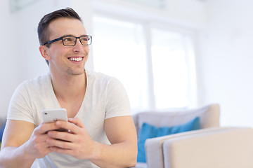 Image showing young man using a mobile phone  at home