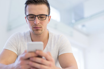 Image showing young man using a mobile phone  at home