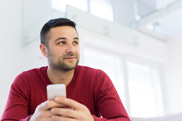 Image showing young man using a mobile phone  at home