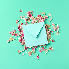 Image showing Mock up craft envelope with floral petals on a turquoisebackground.