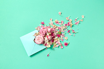 Image showing Fresh pink roses in handmade envelope on a turquoise background.