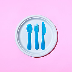 Image showing Served place with eating plastic utensil on a pastel pink background.