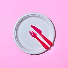 Image showing Served place with disposable plastic utensils on pink.
