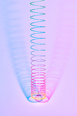 Image showing Vertical rainbow plastic slinky toy with two color shadows.