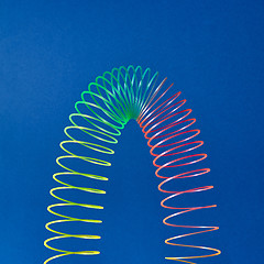 Image showing Flexible plastic rainbow spring on a blue background.