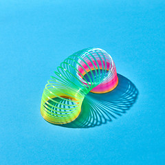 Image showing Toy plastic rainbow slinky with shadows on blue.