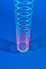 Image showing Vertical stretching plastic slinky toy with two shadows.