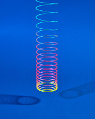 Image showing Hunging colorful plastic toy spiral with two shadows.