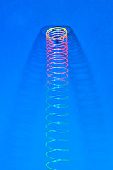 Image showing Hunging rainbow plastic slinky with two shadows.