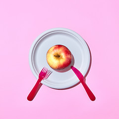 Image showing Fresh apple on a plate served with plastic knife and fork