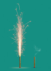 Image showing Two fireworks burning and burnt on a turquoise background.