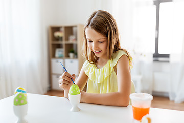 Image showing happy girl coloring easter eggs at home