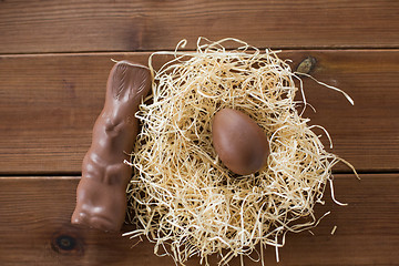 Image showing chocolate bunny and egg in straw nest on wood