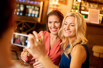 Image showing woman picturing friends by smartphone at wine bar