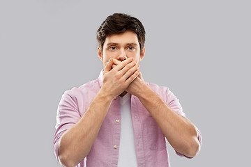 Image showing shocked young man covering his mouth by hands