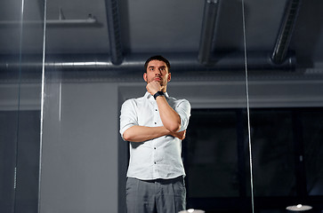 Image showing businessman looking at glass wall at night office