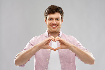 Image showing man making hand heart gesture over gey background