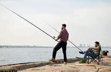 Image showing happy friends with fishing rods on pier