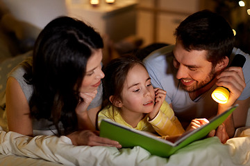 Image showing happy family reading book in bed at night at home