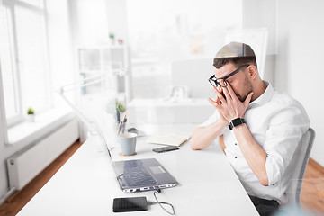 Image showing tired businessman rubbing eyes at office