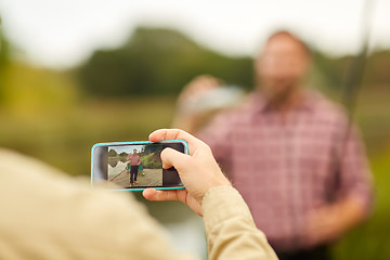 Image showing friend photographing fisherman by smartphone