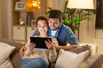 Image showing happy couple using tablet pc at home in evening