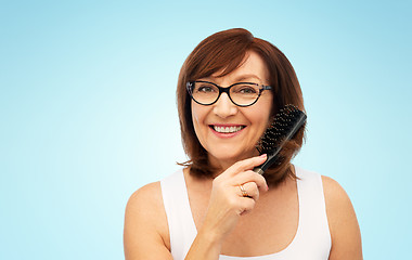 Image showing portrait of senior woman in glasses brushing hair