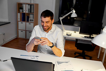 Image showing businessman with smartphone and computer at office