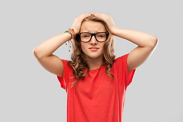 Image showing desperate teenage girl in glasses holding to head