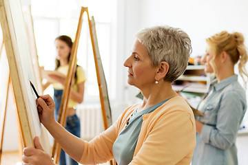 Image showing senior woman drawing on easel at art school studio