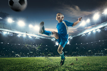 Image showing Young boy with soccer ball doing flying kick at stadium