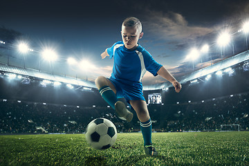 Image showing Young boy with soccer ball doing flying kick at stadium