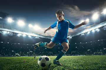 Image showing Young boy with soccer ball doing flying kick at stadium