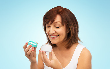 Image showing smiling senior woman with cream jar