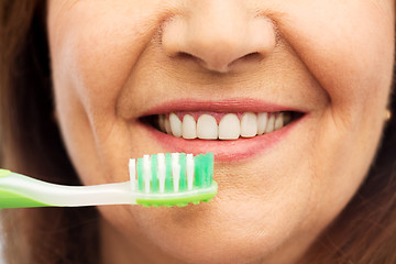 Image showing senior woman with toothbrush brushing her teeth