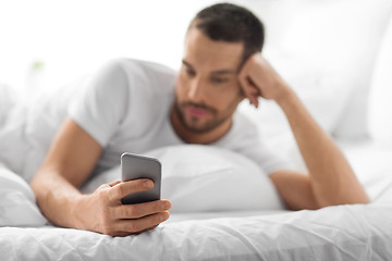 Image showing close up of man with smartphone in bed in morning