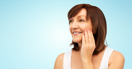 Image showing portrait of smiling senior woman touching her face