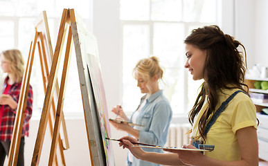 Image showing woman with easel painting at art school studio
